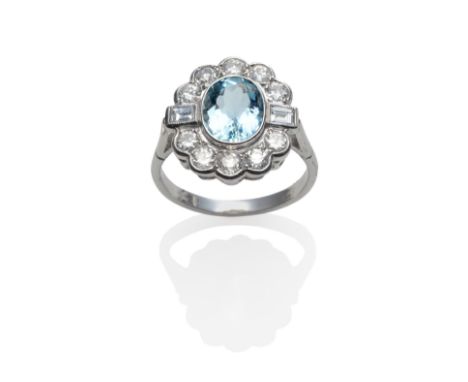 An Aquamarine and Diamond Cluster Ring, the oval cut aquamarine within a border of round brilliant cut and baguette cut diamo