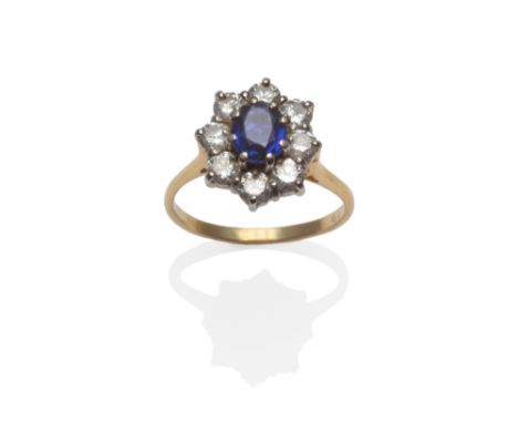 An 18 Carat Gold Sapphire and Diamond Cluster Ring, the oval cut sapphire within a border of eight round brilliant cut diamon