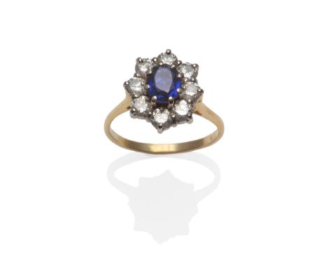 An 18 Carat Gold Sapphire and Diamond Cluster Ring, the oval cut sapphire within a border of eight round brilliant cut diamon