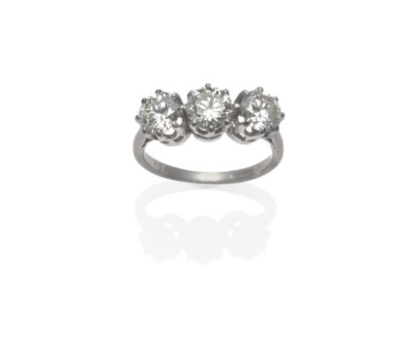 A Diamond Three Stone Ring, the round brilliant cut diamonds in white claw settings, on a tapered shoulder plain polished sha