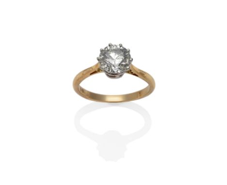 A Diamond Solitaire Ring, the round brilliant cut diamond in a white ten claw setting, to a yellow tapered shoulder plain pol