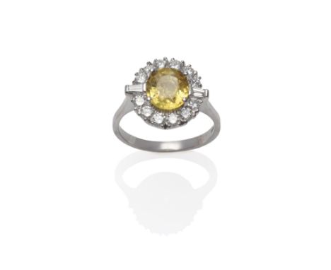 An 18 Carat White Gold Yellow Sapphire and Diamond Ring, the oval mixed cut sapphire within a border of round brilliant cut d