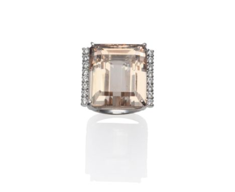 An 18 Carat White Gold Topaz and Diamond Ring, the emerald-cut peachy coloured topaz with a row of round brilliant cut diamon