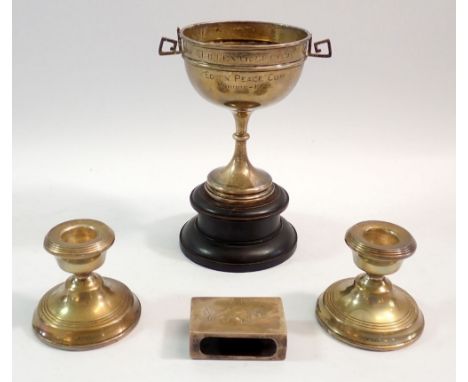 A group of silver items including a Walker &amp; Hall trophy cup on wooden stand, a pair of squat weighted candlesticks and a
