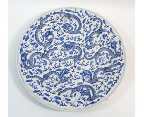A Qing dynasty Chinese blue and white plate painted dragon, four character mark to base, 29cm diameter