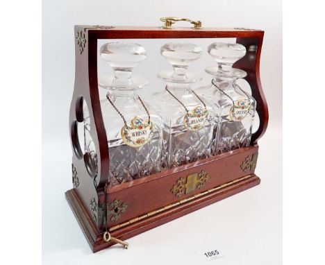A mahogany three bottle tantalus with key and brass mounts 