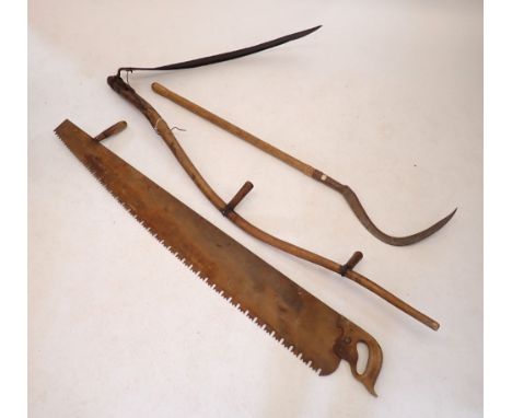 A large scythe and a smaller one plus a large two handled saw 