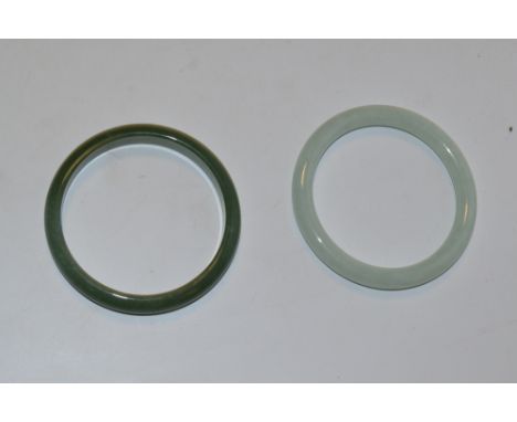 A stained apple green jade slave bangle, 76mm diameter, another lighter 77mm diameter (2)