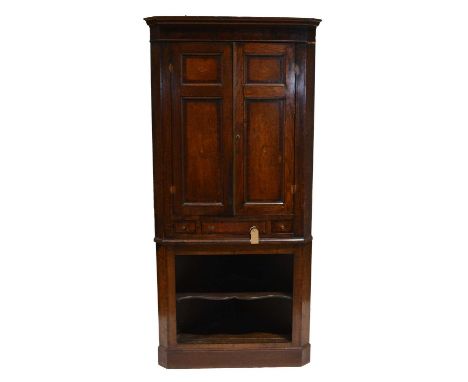 Georgian oak freestanding corner cupboard, moulded cornce, two shell inlaid doors enclosing shelves, frieze drawer above an o