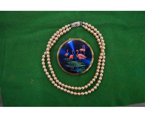 A string of pearls and a decorative compact.