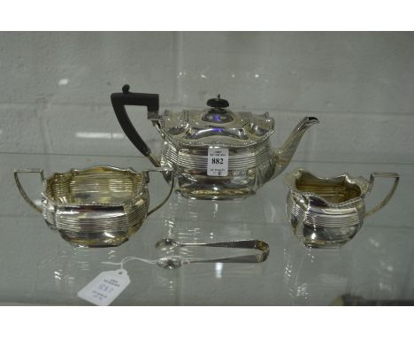 A bachelor's silver three piece tea service of shaped outline with ribbed decoration together with a pair of sugar tongs.