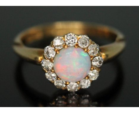 A late Victorian diamond and opal ring, the central precious opal diam. approx. 5.87mm and depth 2.56mm, surrounded by 12 old