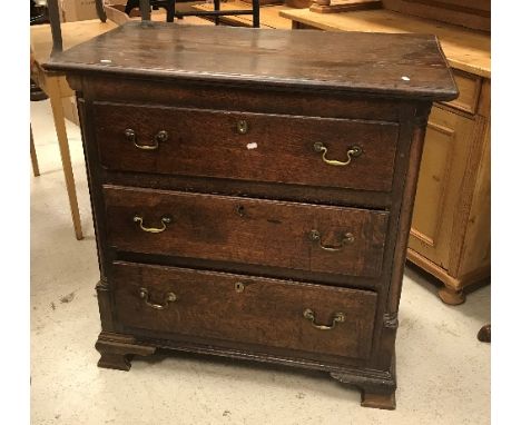 An early 19th Century oak chest, the plank top with moulded edge over three long drawers with brass swan neck handles, raised