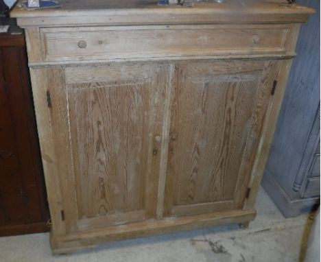 A Continental pine cupboard with single drawer over two cupboard doors enclosing a shelf, raised on bracket feet, 111.5 cm wi