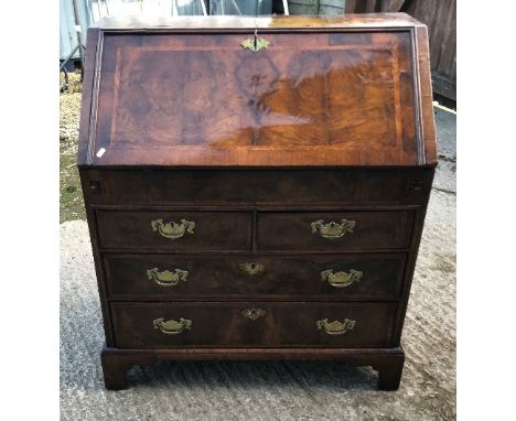 An 18th Century walnut bureau, the feather-banded top and sloping fall enclosing a stepped fitted interior with well over two