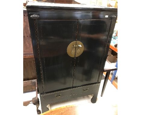 A Chinese black lacquered wedding cabinet, the two doors enclosing two shelves, one with two integral drawers over two furthe