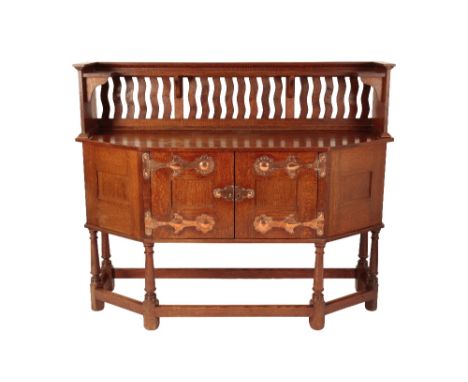 ATTRIBUTED TO LIBERTY &amp; CO: AN ARTS AND CRAFTS OAK SIDEBOARD, shaped rectangular top, above an upright gallery back and s