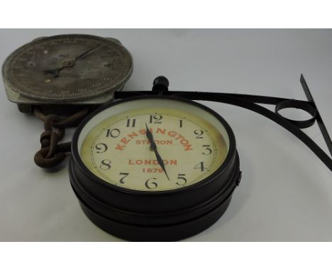 A double sided wall clock in the manner of a station clock, the antiqued cream dials set out in Roman numerals, on a wrought 