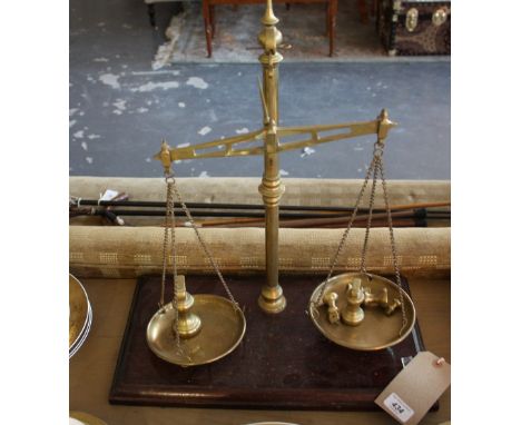 A pair of early 20th century brass balance scale, column support and circular pans on a mahogany base, H. 51cm.