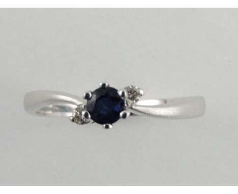 A sapphire and diamond ring, the cross-over setting on a white metal band stamped 14ct, 2g.