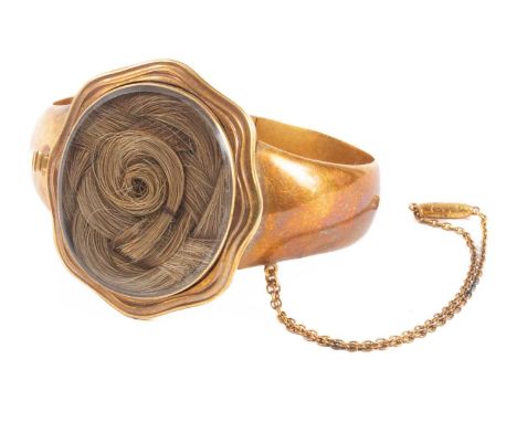 A Victorian gold bangle, centred by a hair set panel and engraved with coronets above initials M and MM, the glazed panel 37m