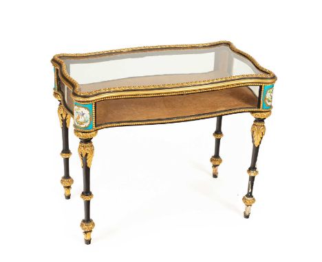 A Napoleon III ebonised and gilt composition vitrine table, with serpentine glazed lifting top and sides and Sèvres pattern m