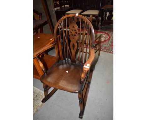 A mid century wheel back Ercol style rocking chair.
