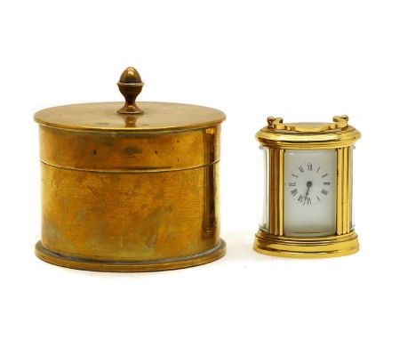 A miniature brass carriage clock of oval form, the white enamel dial with Roman numerals, 8.5cm high, together with a trench 