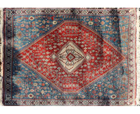 Two hand knotted Persian rugs, the first showing fields of red and blue with central medallion decorated with stylised floral