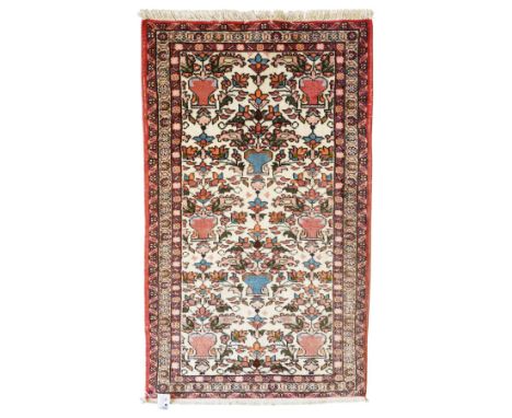 Iranian Persian style rug, repeated stylised vase and floral motifs arranged symmetrically across a ivory field, framed by re