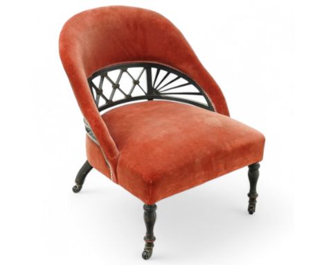 Late Victorian ebonised tub-shaped nursing chair, lattice and fanned back upholstered in rouge fabric, on turned front feet w