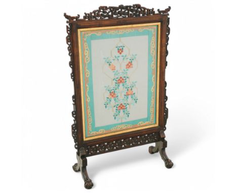 Early 20th century stained beech Chinese hardwood fire screen, the frame decorated fretwork and carved foliage, needlework pa