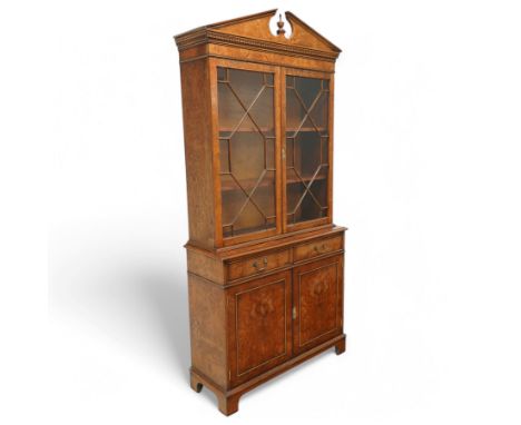 Georgian design burr walnut bookcase cabinet over chest with panelled cupboards and two drawers, arched pediment above a dent