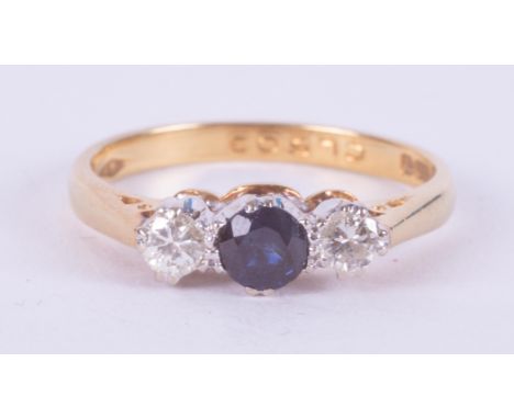 An 18ct yellow gold three stone ring set with a central round cut sapphire and a round brilliant cut diamond to either side, 