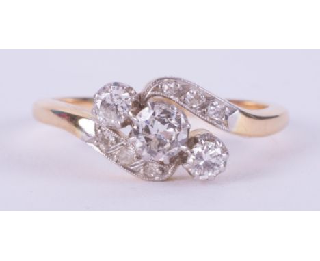 An 18ct yellow gold &amp; platinum crossover style ring set with three round brilliant cut diamonds surmounted by smaller rou