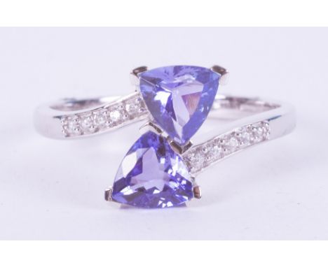 A 9ct white gold ring set with two triangular cut tanzanite's, AA quality, 1.50 carats with 0.13 carats of round white zircon