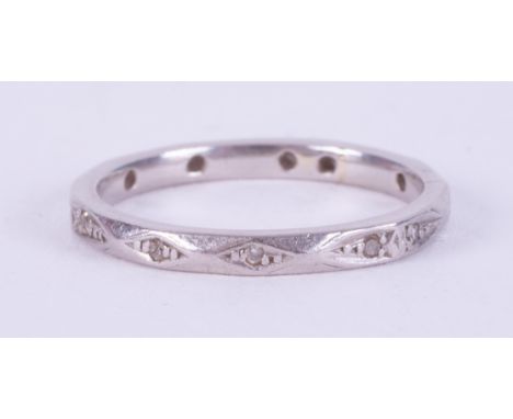 A platinum bevelled design eternity ring set with tiny round cut diamonds spaced around the band, 3.00gm, size J 1/2 to K.