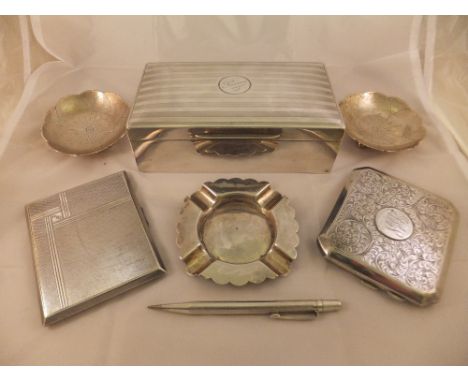 A collection of smoking requisites to include a silver sheathed table cigarette box, two silver cigarette cases, silver ashtr