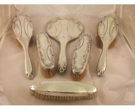 A five piece dressing table set comprising hand mirror and four brushes (Birmingham, 1910, 1911 and 1935), together with a fu