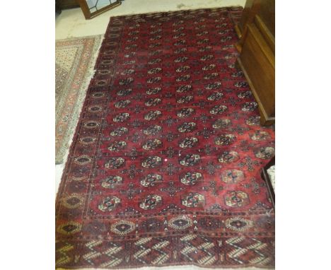 A  Bokhara carpet, the central red field decorated with elephant foot medallions in cream and dark blue/black within dark red