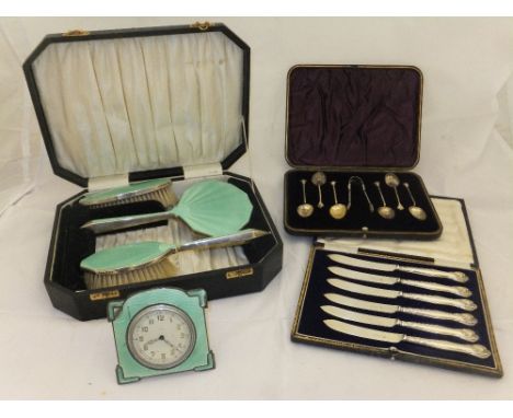 An Art Deco cased travelling set comprising travelling clock, hand mirror, clothes brush and hairbrush, each with silver moun