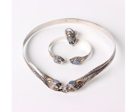 A silver necklace, bracelet and a ring with opal settings and gold detailing, stylised serpent design 