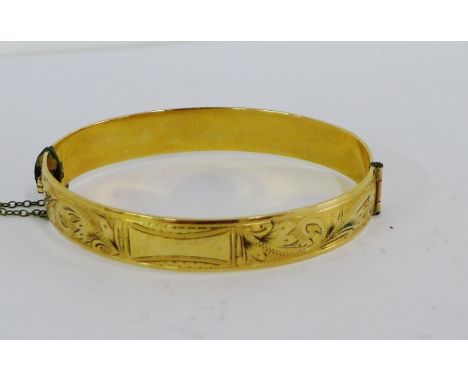 A vintage gold plated stiff hinged bangle with bright cut engraving 