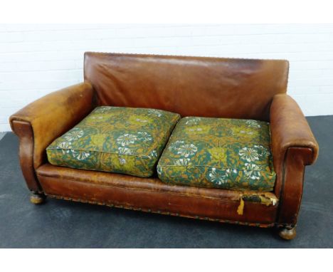 An early 20th century brown leather two seater sofa with upholstered cushions and bun feet,  73 x 160cm