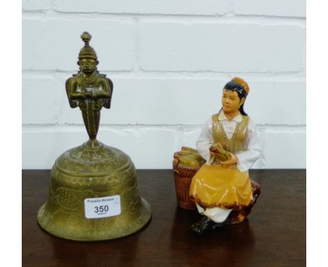 A brass Thai style bell, together with a ceramic figure, (2) 