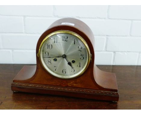 A mahogany cased mantle clock, the silvered dial with Arabic numerals over a foliate inlaid panel on four bun feet