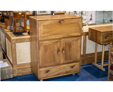 An Ercol Cabinet With Fall Front Above Cupboard Space and Single Drawer To Base. Raised on Casters. Height 43 inches, 32 x 17