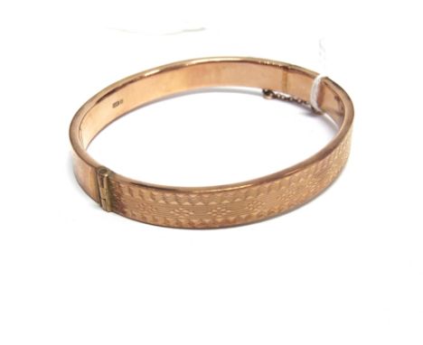 A 9 CARAT ROSE GOLD HINGED BANGLE  Chester 1923, the frontispiece with engine turned decoration, inner diameter 6cm, 9.3g gro