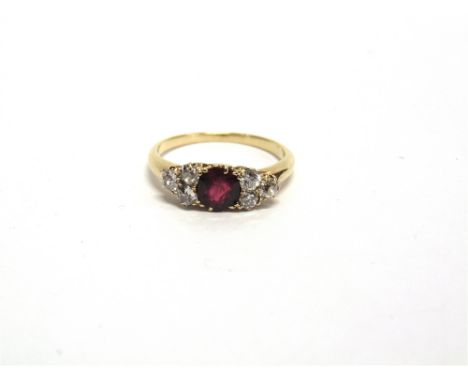 A RUBY AND DIAMOND RING unmarked, the round cut ruby, of approximately 5.7mm by 2.4,, deep, flanked either side by a trio of 