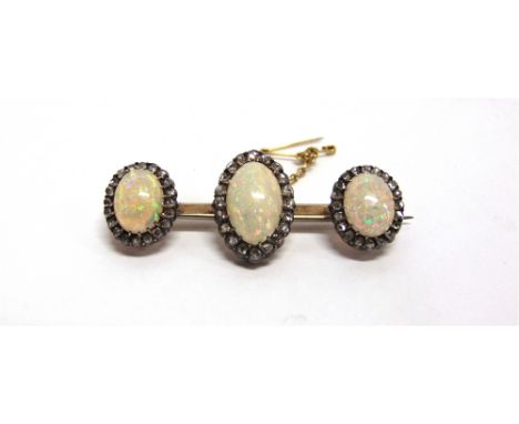 AN OPAL AND DIAMOND TRIPLE CLUSTER BAR BROOCH circa 1900, the graduated oval cabochons enclosed by silver collet set rose cut